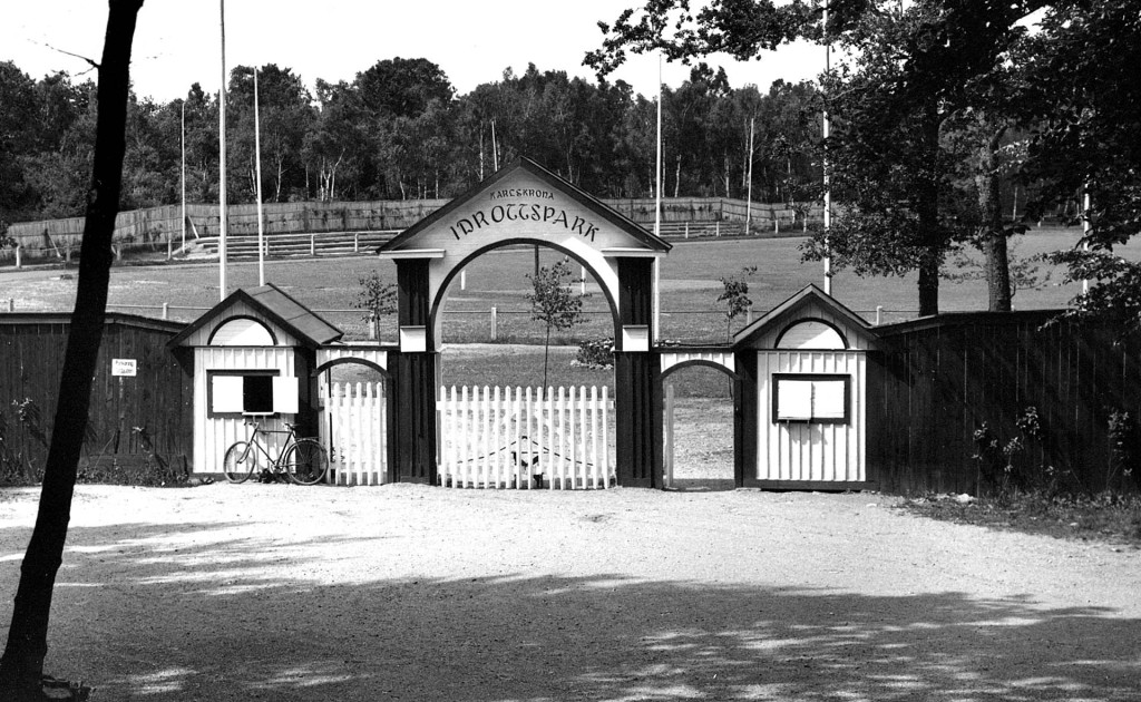 Bilden visar Karlskrona Idrottspark på Västra Mark och den dåvarande entrén till anläggningen. Bilden bör vara tagen några år efter den högtidliga invigningen den 13 september 1925.